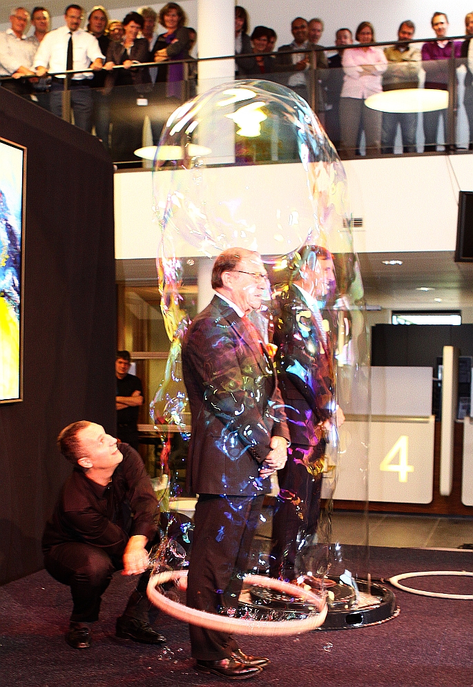 ... , zelfs niet die waarin de beide cdk's stonden en waarvan de paar seconden dat die bestond de opening van het BEL-kantoor onderstreepten, maar waarvan het ploffen even later natuurlijk een bedenkelijke symboliek was die de feestvreugde evenwel niet drukte en het proosten, ballen snaaien en netwerken kon aanvangen.