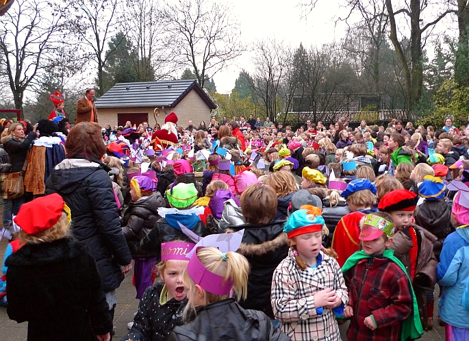 even later een schoolplein vol pepernootgraaiende kinderen - goedkeurend gadegeslagen door ouders en verzorgers